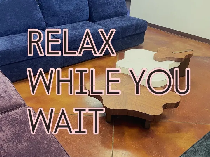 Plush couches and sculptural coffee tables in The Fuge Auto Spa lounge, with the words Relax While You Wait